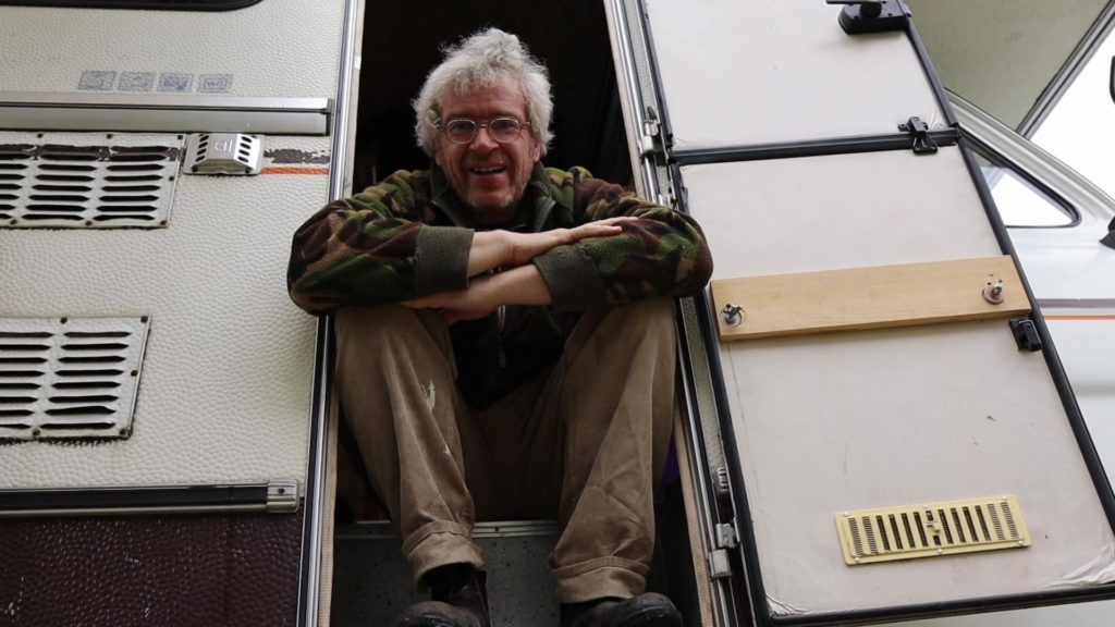 Thomas Beeskow im Ford Transit Wohnmobil Thomas freut sich in der Tür sitzend das das Heck vom Ford Transit Wohnmobil wieder geschlossen ist