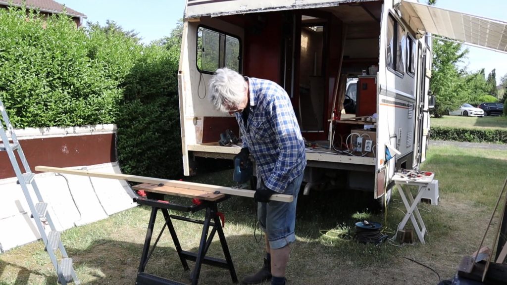 Thomas sägt mit der Stichsäge auf der mobilen Werkbank die Holzleisten für das neue Wohnmobil Heck passend zu