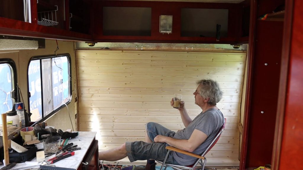 Thomas macht eine Kaffeepause vor der neuen Rückwand aus Holzpanelen